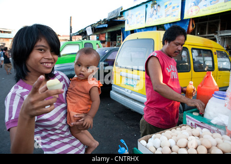 Woman with her baby, she is buying Balut, a fertilized duck embryo from a roadside vendor. Carbon Market, Cebu City, Philippines Stock Photo