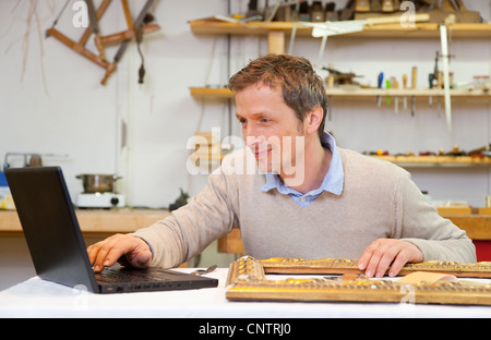 Carpenter working on laptop in shop Stock Photo