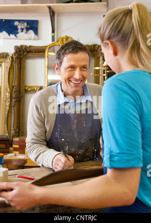Carpenter talking to woman in shop Stock Photo