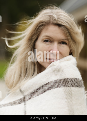 Woman wrapped in blanket outdoors Stock Photo