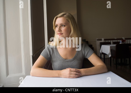 Woman sitting at table indoors Stock Photo