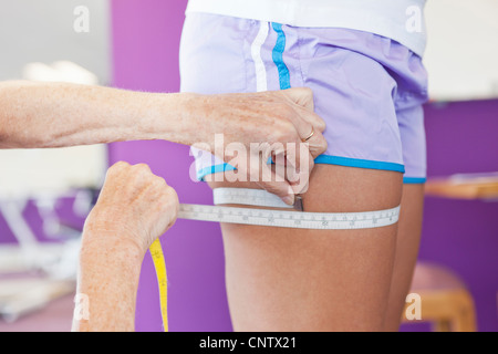 Trainer measuring girls leg in gym Stock Photo
