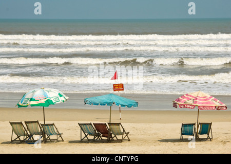 Horizontal view of a line of tatty deckchairs and parasols along Da Nang, Danang or Đà Nẵng beach in Vietnam Stock Photo