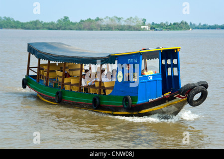 Horizontal view of a small ferry boat with local Vietnamese passengers travelling along the Mekong Delta, Vietnam. Stock Photo