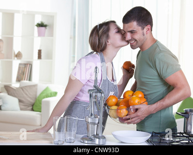 Woman kissing boyfriend in kitchen Stock Photo