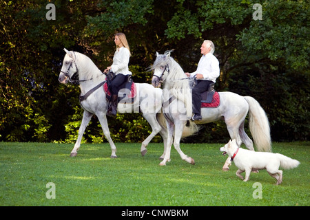 two rider on white horses with dog in a park, Germany