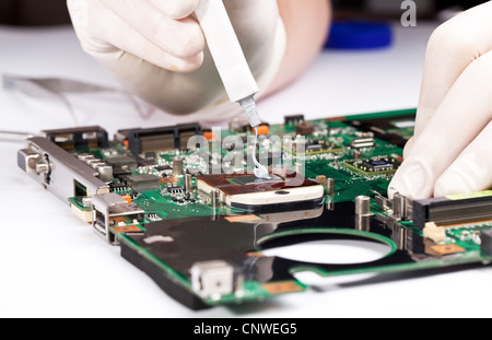 Man in white gloves Installing laptop thermal compaund on processor Stock Photo