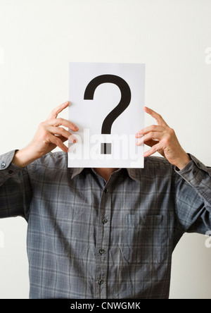 Man with question mark covering face. Stock Photo