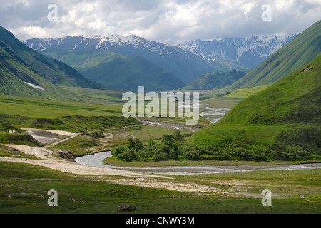 view over wide valley with river in front of mountain panorama, abandonned village and mediaeval fortress in the distance, Georgia, Truso-Tal Stock Photo