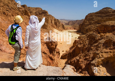 bedouin guide showing a tourist  the canyon landscape of Sinai desert from a hill, Egypt, Sinai Stock Photo