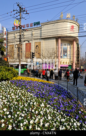 Spring flowers in municipal flowerbeds, modern shops and crowded electricity powerlines in suburban Shanghai, China. Stock Photo