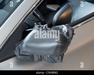 Side mirror of Aston Martin sportscar being wrapped with carbon-look foil Stock Photo