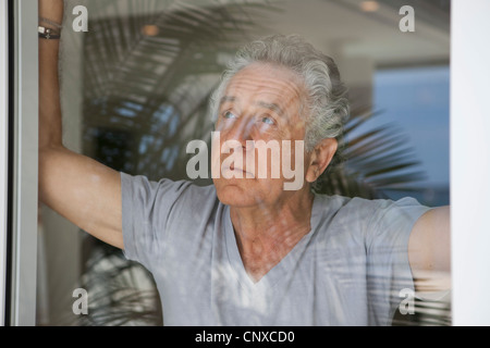 A senior man looking out a window Stock Photo