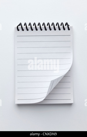 A spiral notepad with lined paper and a curled up page corner Stock Photo