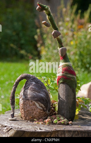 'felt stone trolls' serving as garden decoration: two natural stones equipped with caps of felted wool standing side by side on a tree snag, Germany Stock Photo