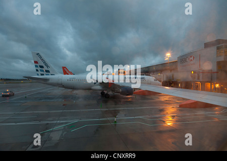 Strategic Airlines aircraft on stand at Gatwick Airport South Terminal in he early morning on a wet and stormy day Stock Photo