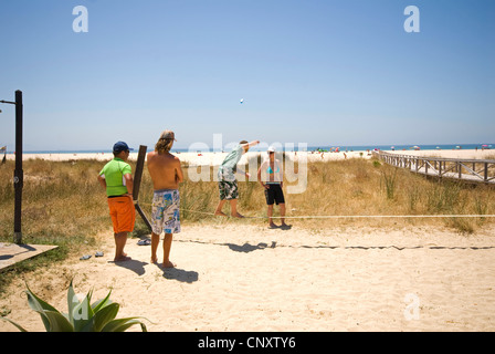 Teenagers walking tightrope at beach bar Stock Photo