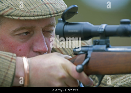 deer stalker hunting reed deers aiming with his gun, United Kingdom, Scotland, Cairngorms National Park Stock Photo