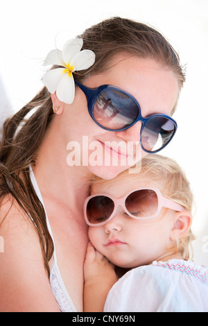 frangipani plant, nosegaytree (Plumeria alba), young mother with frangipani blossom in the hair and little daughter in the arms cuddling up to her sleeping