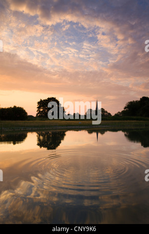Salisbury Cathedral Spire and a beautiful dawn sky reflected in a rippled pond, Salisbury, Wiltshire, England. Stock Photo