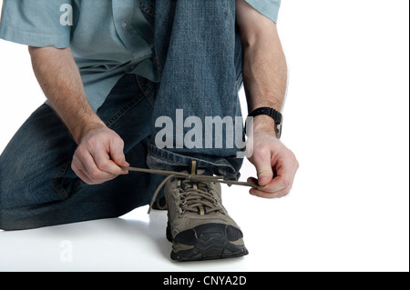 man in jeans squats down to tie his athletic shoe isolated on white Stock Photo