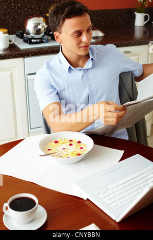 Vertical shot of a man reading morning newspaper at breakfast Stock Photo