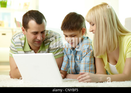 Cheerful family of three using laptop together Stock Photo