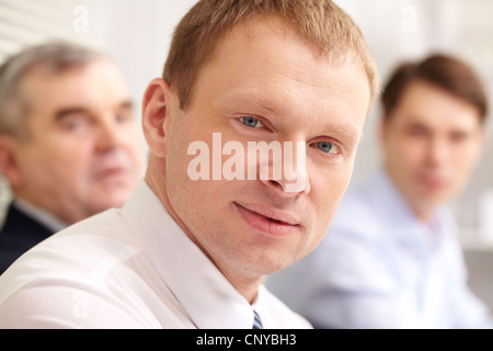 Businessman in the foreground looking confidently at camera Stock Photo