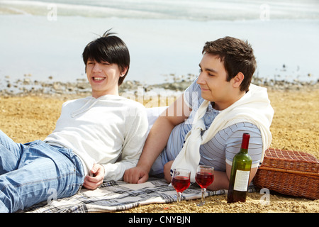 Homosexual couple enjoying themselves having a picnic at seaside Stock Photo