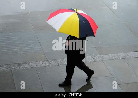 Man walking in rain with umbrella, London UK Stock Photo