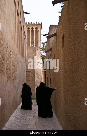 Two Arab women in traditional dress among the windtowers in Bastakiya, Dubai, United Arab Emirates Rear view. Stock Photo