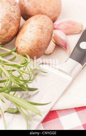 Chestnut mushrooms, Rosemary and kitchen knife on a cutting board Stock Photo