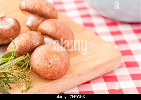 Chestnut mushrooms and Rosemary on a cutting board Stock Photo