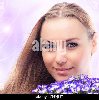 Girl face with bouquet of spring plant, bunch of purple cornflowers, lovely woman with gift over pink abstract background Stock Photo