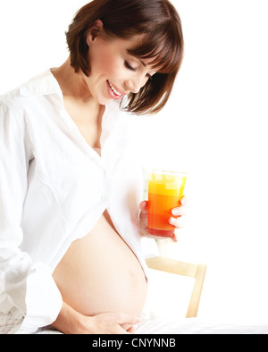 Healthy pregnant lady drinking orange juice, happy mother waiting for a new baby, pretty female isolated on white background Stock Photo