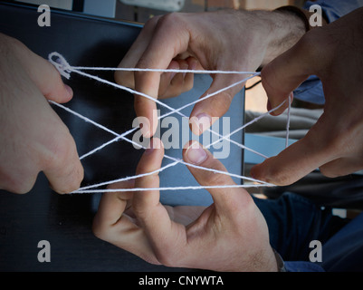 Hands playing cat's cradle with piece of string Stock Photo