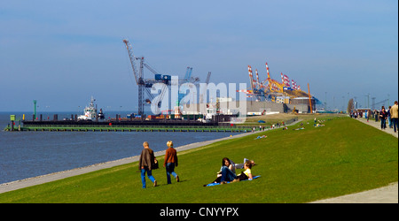 people on the Weser promenade on the dyke. In the background the berth for the cargo ships and the Pingelturm, Germany, Bremerhaven Stock Photo