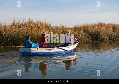 three Quechua or Uros Indians in a rowing boat on Lake Titicaca, Peru, Uros Island Stock Photo