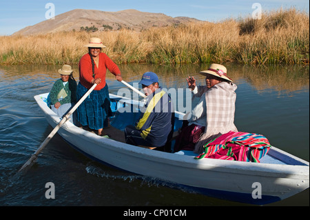 four Quechua or Uros Indians in a rowing boat on Lake Titicaca at one of 42  floating islands called 'Uros Islands', Peru, Uros Island Stock Photo