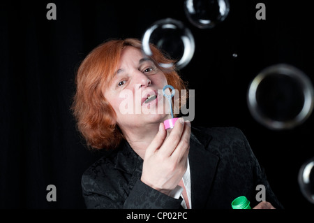Middle aged woman blowing bubbles Stock Photo