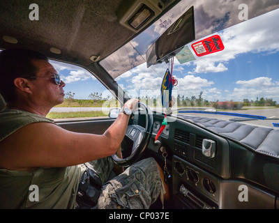 A 30-40 year old Hispanic Cuban male is viewed driving his car along the highway from the inside of the car in western Cuba. Stock Photo