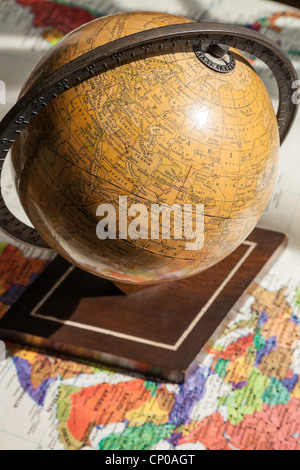 Vintage 1930's World Globe on Stand on current world map. Stock Photo