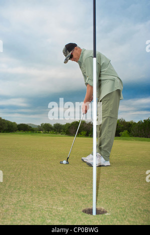 Golfer using putter at golf game Stock Photo