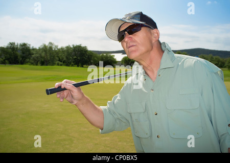 Older golf player watching his ball after hitting Stock Photo