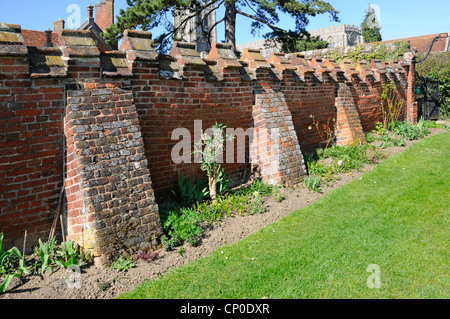 Old brick boundary wall supported by buttresses Stock Photo