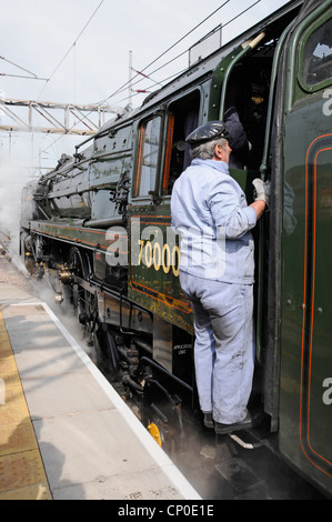 Britannia 70000 steam locomotive built in 1951 on charter run with driver about to return to footplate after a water refill Stock Photo