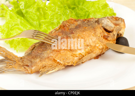 fried carp fish on a plate on the table, submitted