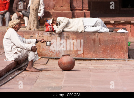 Fatehpur Sikri, Uttar Pradesh, India. One Man Sleeping, One Yawning, in Courtyard of Jama Masjid (Dargah Mosque). Stock Photo