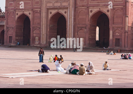 Fatehpur Sikri, India. Men Sitting in Courtyard of Jama Masjid (Dargah Mosque). Buland Darwaza (Great Gate) in Background. Stock Photo