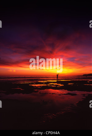 A sea fisherman casting his beach rod at sunset. Oura beach near Albufeira, Algarve Portugal. Stock Photo